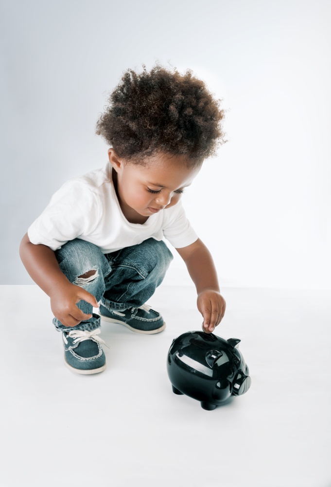 Portrait of a Nice African American Child Putting Coins in to the Pig-shaped Money Box. Isolated on Grey White Background. Hope for Better Future