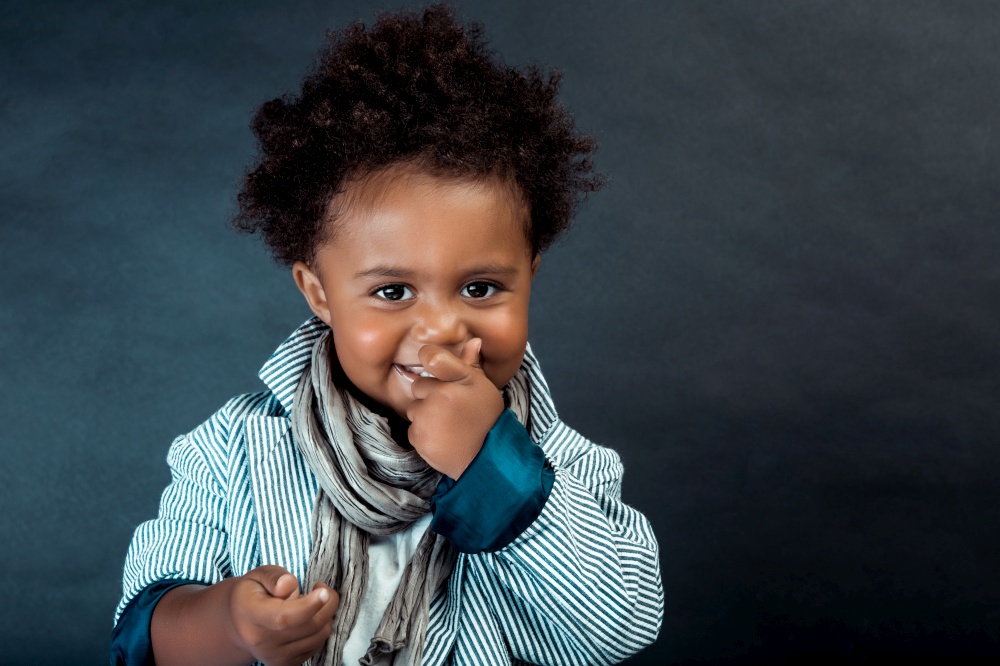 Portrait of a Nice Little African-American Boy Dressed in Stylish Clothes Posing over Dark Background in the Studio. Baby Model.
