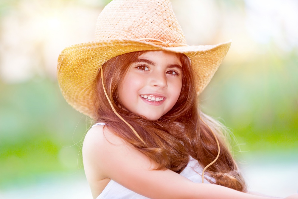 Portrait of ? cute happy little girl wearing stylish straw hat, having fun outdoors, spending summer holidays on the farm