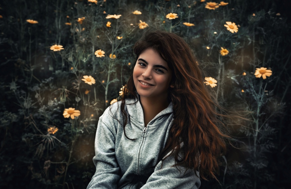 Portrait of a beautiful teen girl with pleasure spending time on a flowers field, enjoying fresh spring nature, spare time in countryside, happy springtime holidays