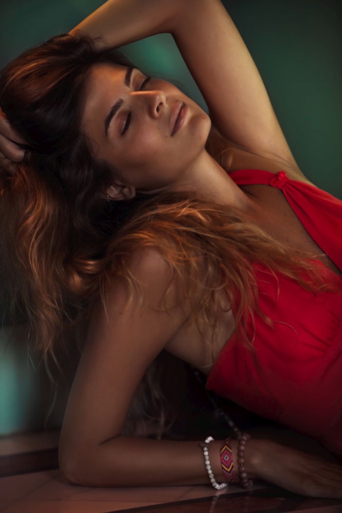 Portrait of an Attractive Female with Closed Eyes Dressed in Gorgeous Red Dress. Beautiful Young Woman with Long Hair and Perfect Skin. Female Fashion Look.