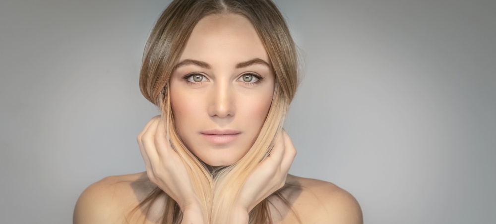 Authentic portrait of a beautiful blond woman isolated on gray background, genuine beauty of a young adult female, natural makeup and fashion look, photo with copy space, panoramic photo format