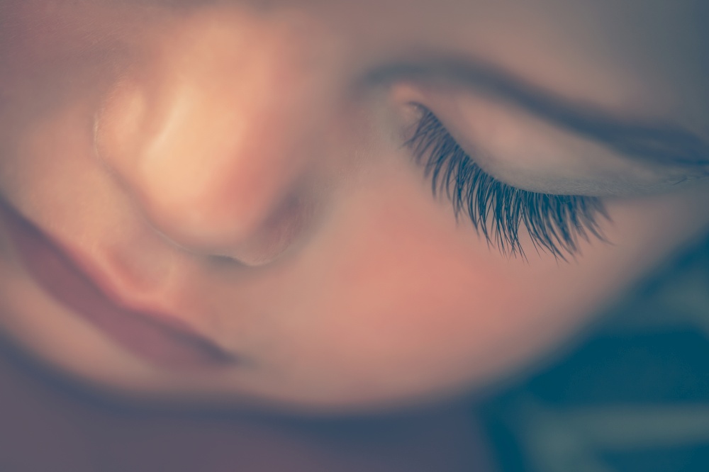 Closeup portrait of an adorable newborn child sleeping at home, face part, cute baby face, new life concept