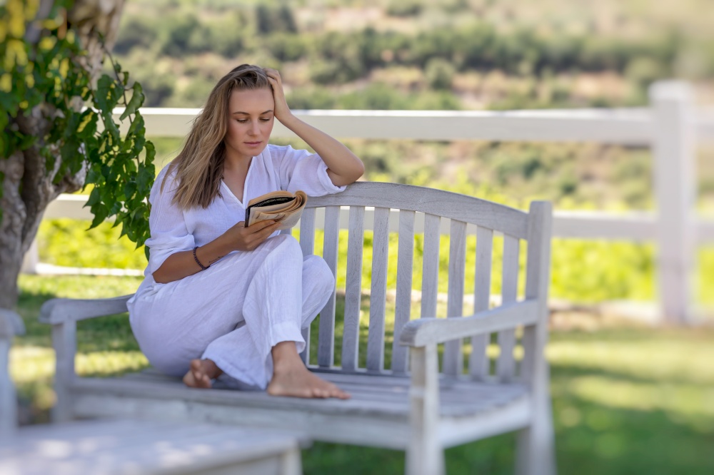 Beautiful Girl Reading Book Outdoors. Nice Female Spending Leisure Time in Countryside Ranch. Perfect Place to Enjoying Calm Summer Vacation.