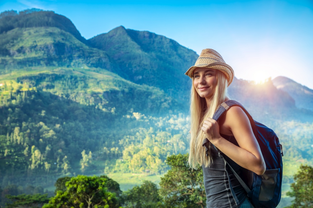 Traveler woman with backpack standing over high green mountain background, enjoying exotic summer vacation, Sri Lanka
