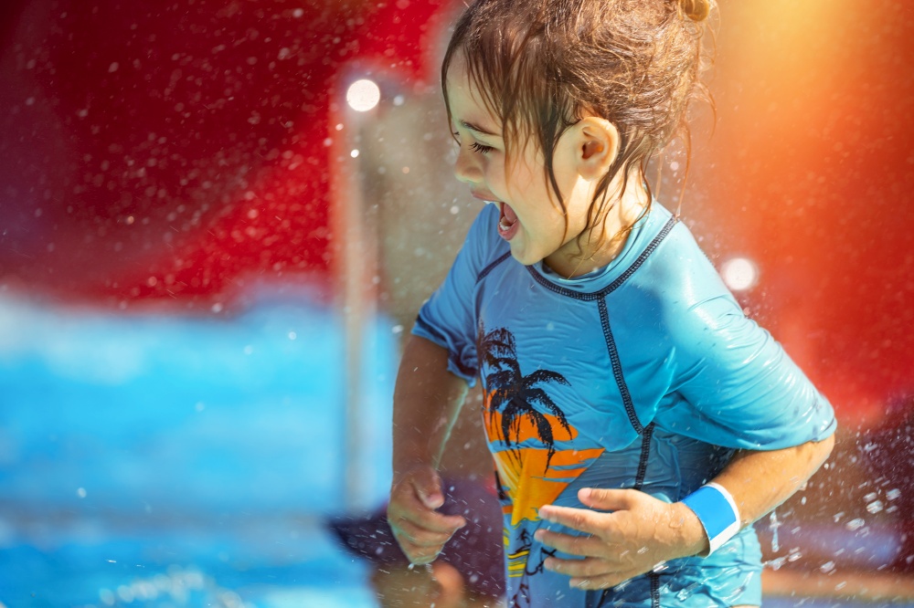 Cheerful Little Boy Having Fun in Waterpark on the Beach Resort. With Pleasure Making Water Splashes. Happy Summer Holidays.. Little Boy in Waterpark