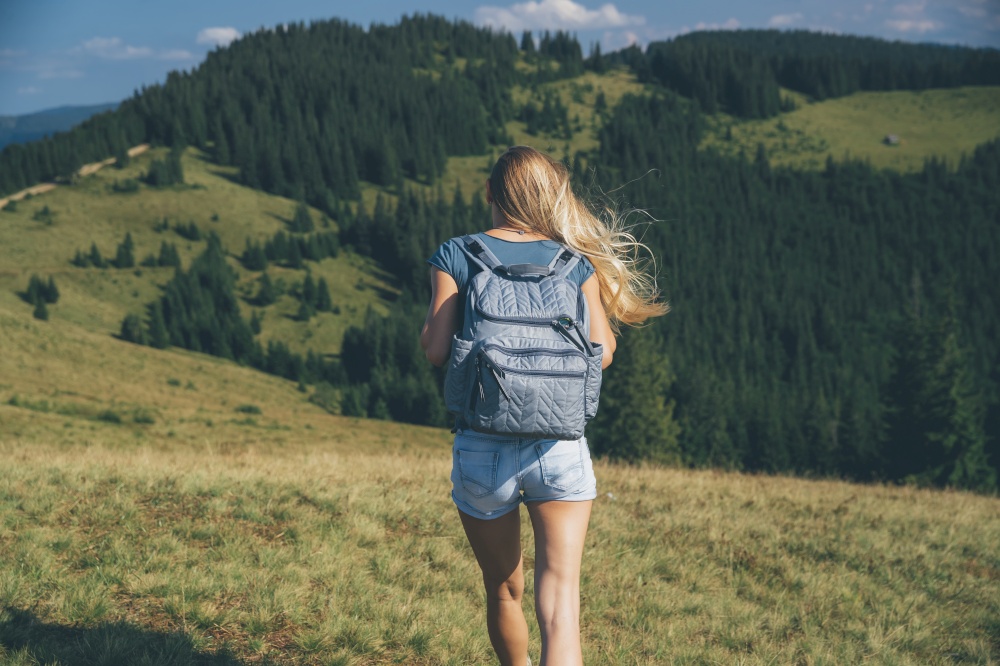 Rear View of a Sportive Girl Walking in the Mountains. Traveling along Amazing Fresh Mountainous Nature. Active Sportive Life. Carpathian. Ukraine. Traveler Woman in the Mountains