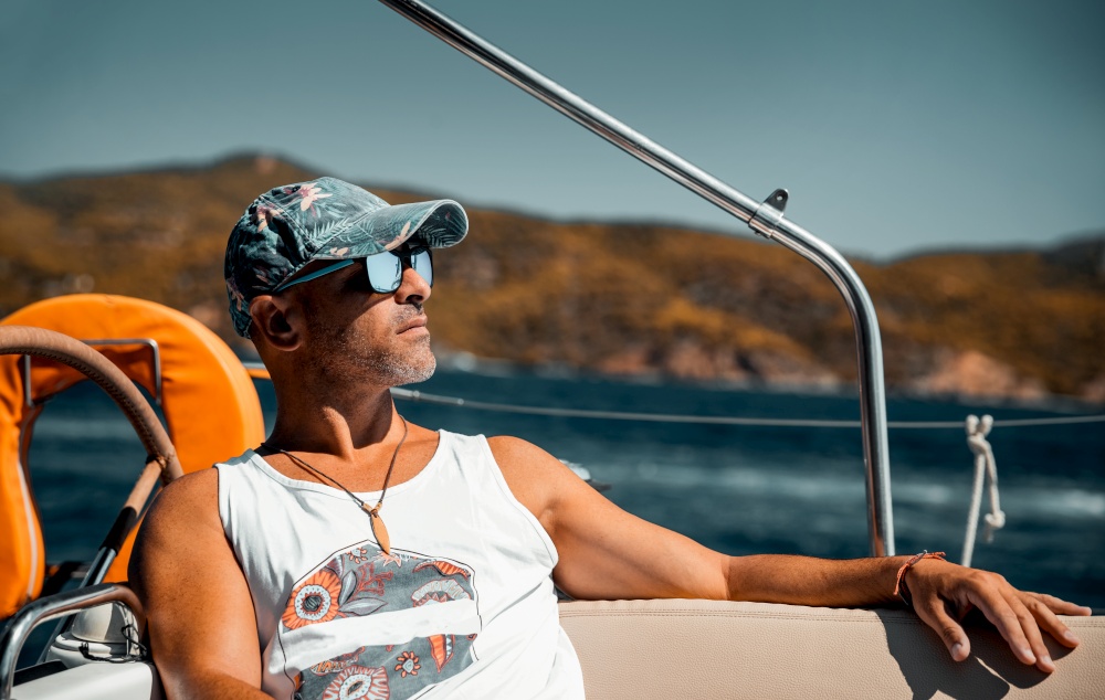 Portrait of a Handsome Man Relaxing on the Sailboat. Enjoying Bright Warm Sunny Day in Luxury Water Cruise. Happy Summer Holidays in Greece.. Man Relaxing on Sailboat