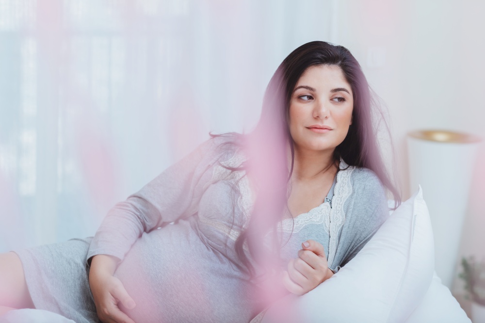 Nice Pregnant Woman with Pleasure Spending Time at Home. Resting on the Bed. Happy Healthy Mother to Be. Family Love Concept.. Beautiful Pregnant Woman at Home