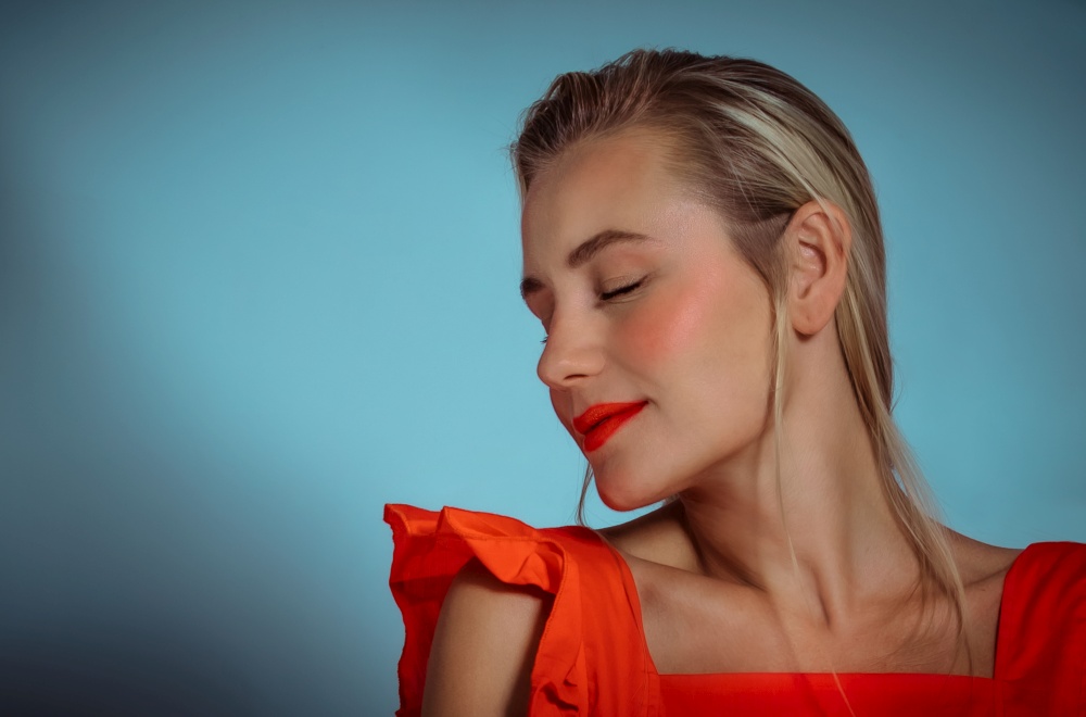 Closeup Portrait of a Beautiful Blond Woman with Bright Makeup. Wearing Red Stylish Clothes Isolated on a Blue Abstract Background. Fashion Look.. Fashion Woman Portrait