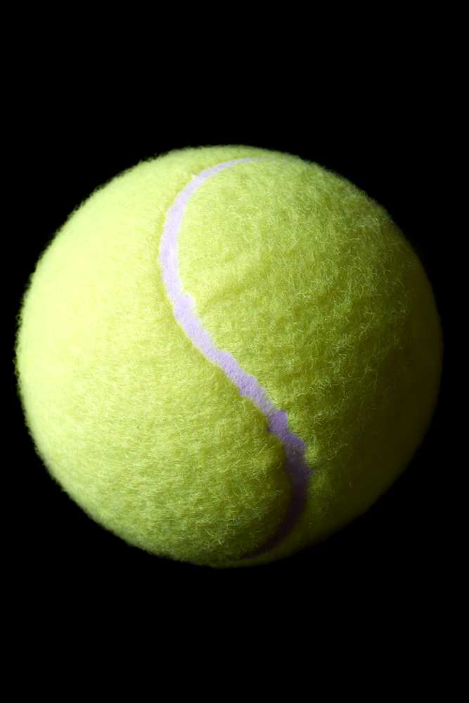 Close up of green tennis ball on black background