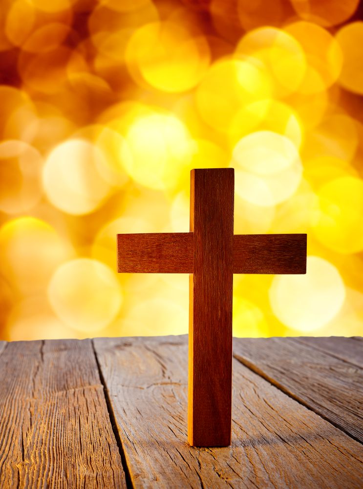 Christian wood cross on blur flare lights and wooden background
