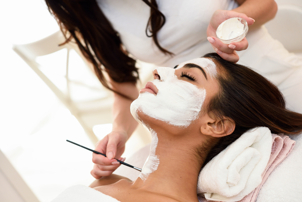 Aesthetics applying a mask to the face of a beautiful woman in modern wellness center. Beauty and Aesthetic concepts.
