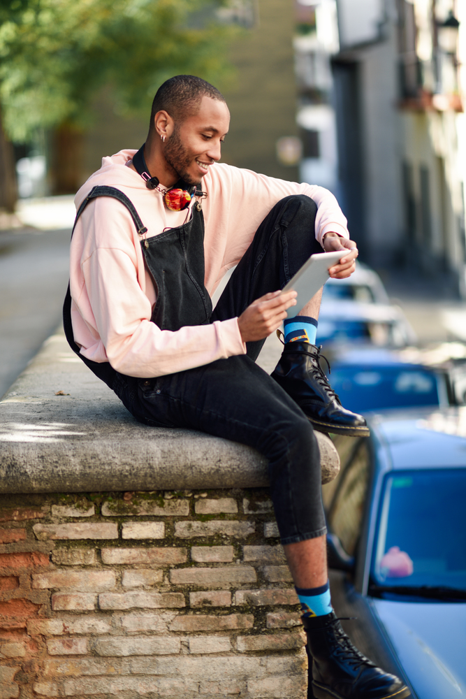 Young black man using digital tablet in urban background. Lifestyle and technology concepts.. Young black man using digital tablet in urban background.
