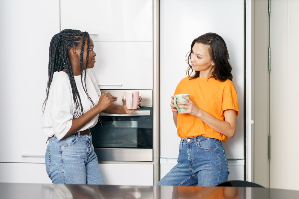 Two student friends taking a coffee break together at home Multiethnic women.. Two student friends taking a coffee break together at home.