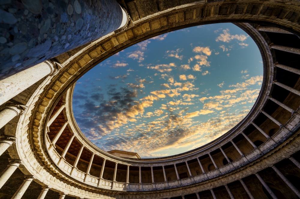 View upwards of the interior of the Palace of Carlos V in the Alhambra in Granada with a dramatic cloudy sky at sunset. Interior of the Palace of Carlos V in the Alhambra in Granada with a dramatic cloudy sky at sunset