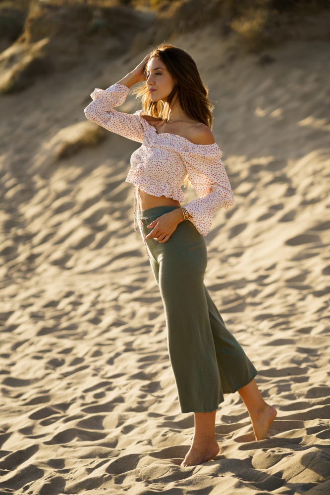 Young beautiful woman standing on the sand of the beach wearing casual clothes.. Young beautiful woman standing on the sand of the beach