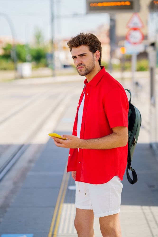 Student male waiting for a train at an outside station. Young man waiting for a train at an outside station