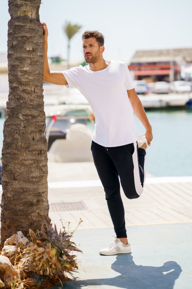 Young man stretching after exercise in a harbour. Man stretching after exercise in a harbour