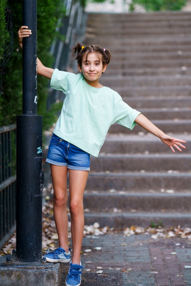 Nine-year-old girl standing on the steps of a city park.. Nine-year-old girl standing on the steps outdoors