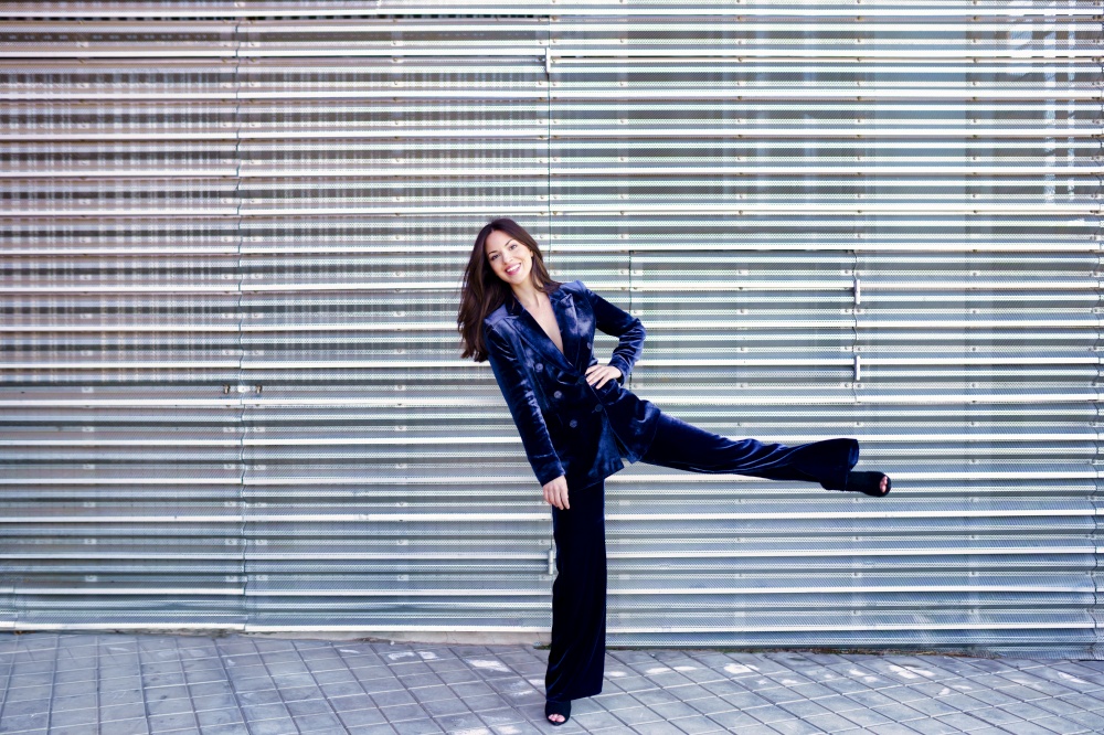 Woman wearing blue suit posing near a modern metal building. Lifestyle concept.. Woman wearing blue suit posing near a modern metal building.