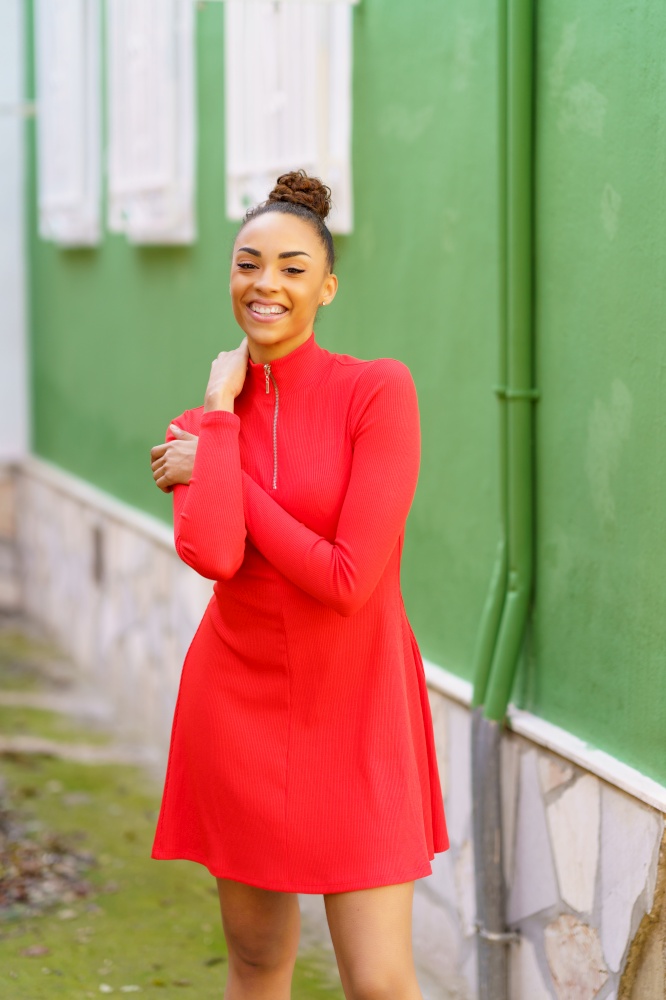 Happy young black woman in red dress in front of a green wall. Happy black woman in red dress in front of a green wall