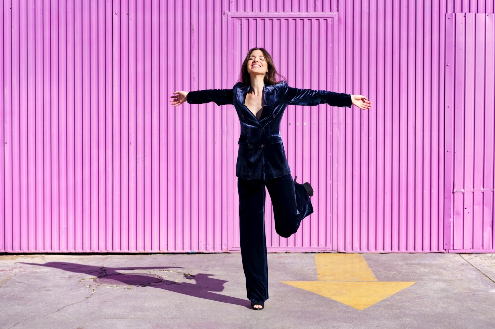 Woman wearing blue suit dancing near pink shutter. Fashion concept.. Woman wearing blue suit dancing near pink shutter.