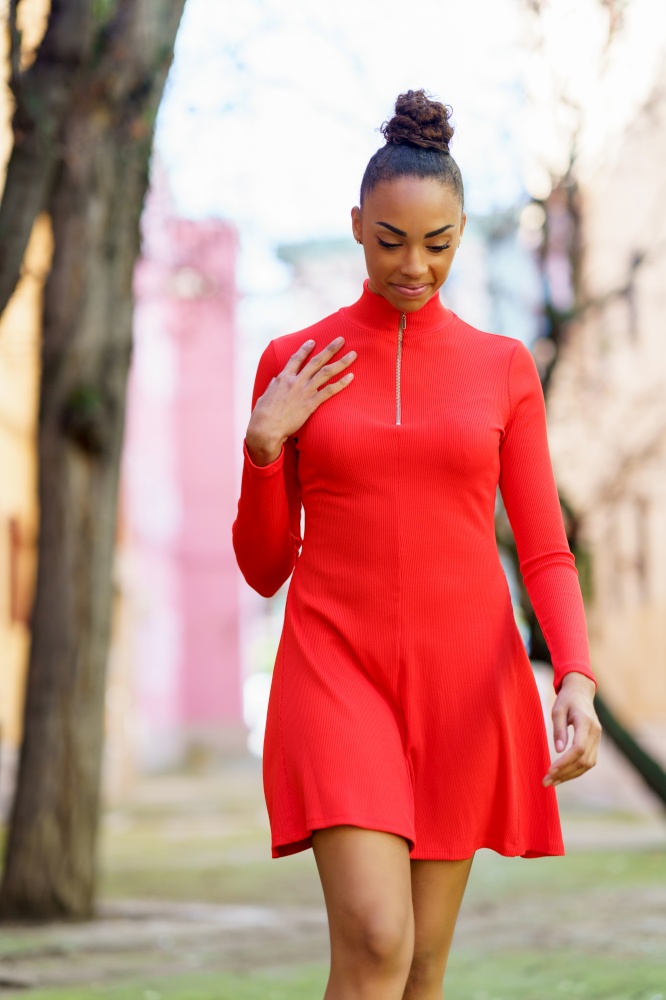 Smiling young mixed woman in red dress walking down the street. Smiling mixed woman in red dress walking down the street
