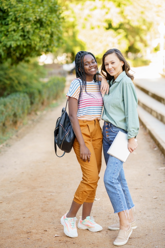 Two multiethnic female friends posing together with colorful casual clothing outdoors. Mutliethnic women.. Two multiethnic women posing together with colorful casual clothing