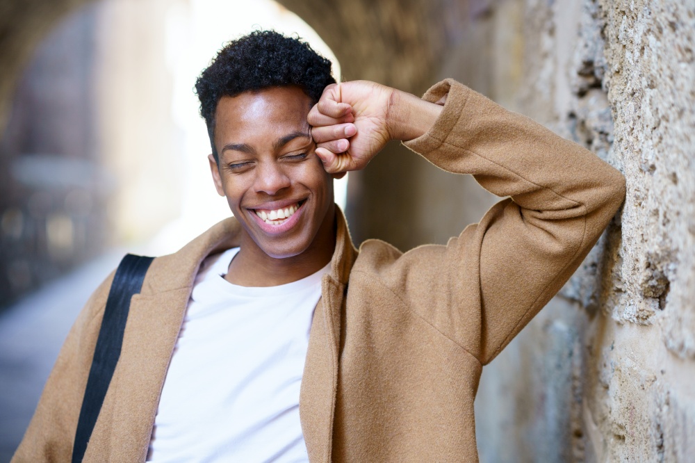 Happy black man laughing outdoors. Cuban student in urban background.. Happy young black man laughing in urban background.