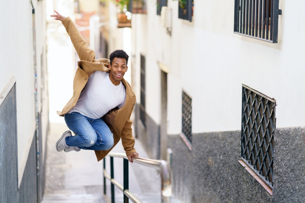 Young black man jumping for joy over a handrail in the street. Cuban guy.. Young black man jumping for joy over a handrail in the street.