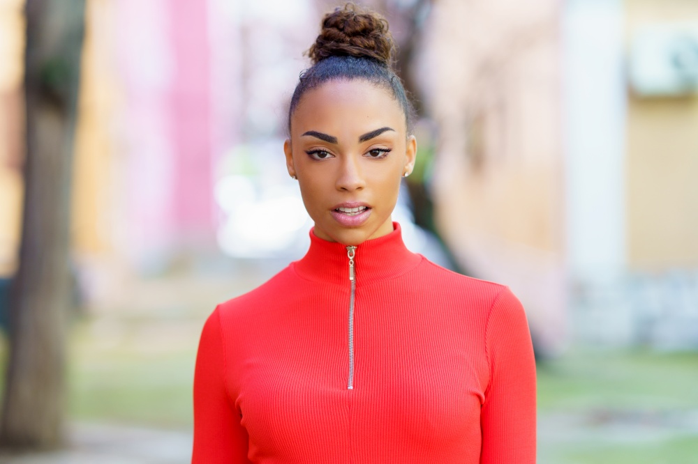 Portrait of a beautiful young black woman in red dress posing on a street with colorful walls. Young black woman in red dress posing on a street with colorful walls
