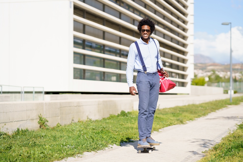 Black businessman riding skateboard near office building. Guy with afro hair.. Black businessman riding skateboard near office building.