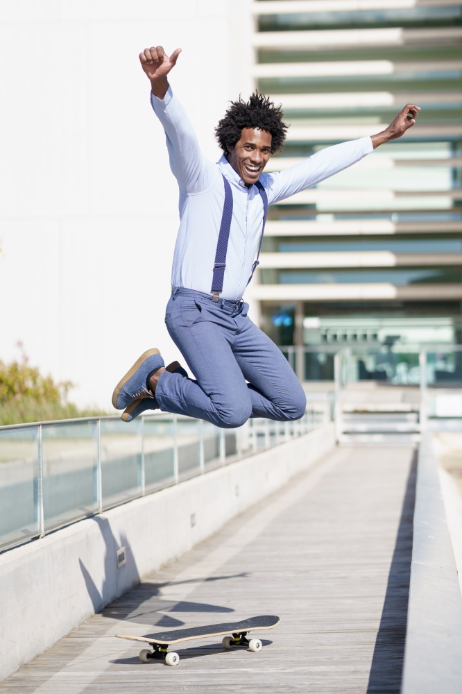 Black businessman jumping on a skateboard near an office building. Guy with afro hair.. Black businessman jumping on a skateboard near an office building.