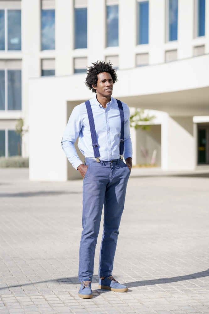 Black businessman with afro hairstyle wearing shirt and suspenders standing near an office building.. Black businessman wearing shirt and suspenders standing near an office building.