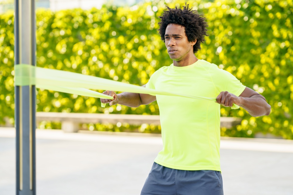 Black man working out with elastic band outdoors. Young male exercising in urban background.. Black man working out with elastic band outdoors