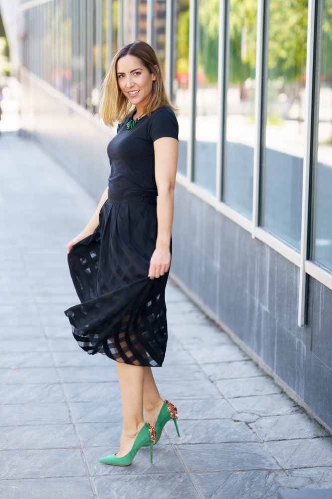Attractive woman wearing skirt and green high heels on the street.. Attractive woman wearing skirt and green high heels outdoors.