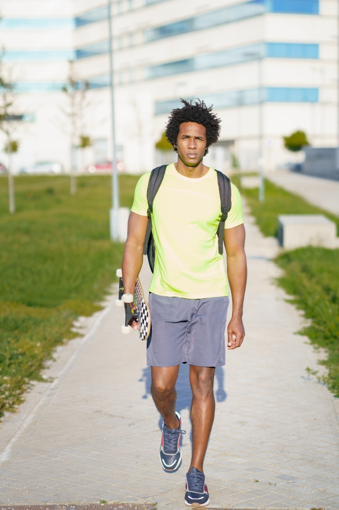 Black man with afro hair, going for a workout in sportswear and a skateboard.. Black man going for a workout in sportswear and a skateboard.