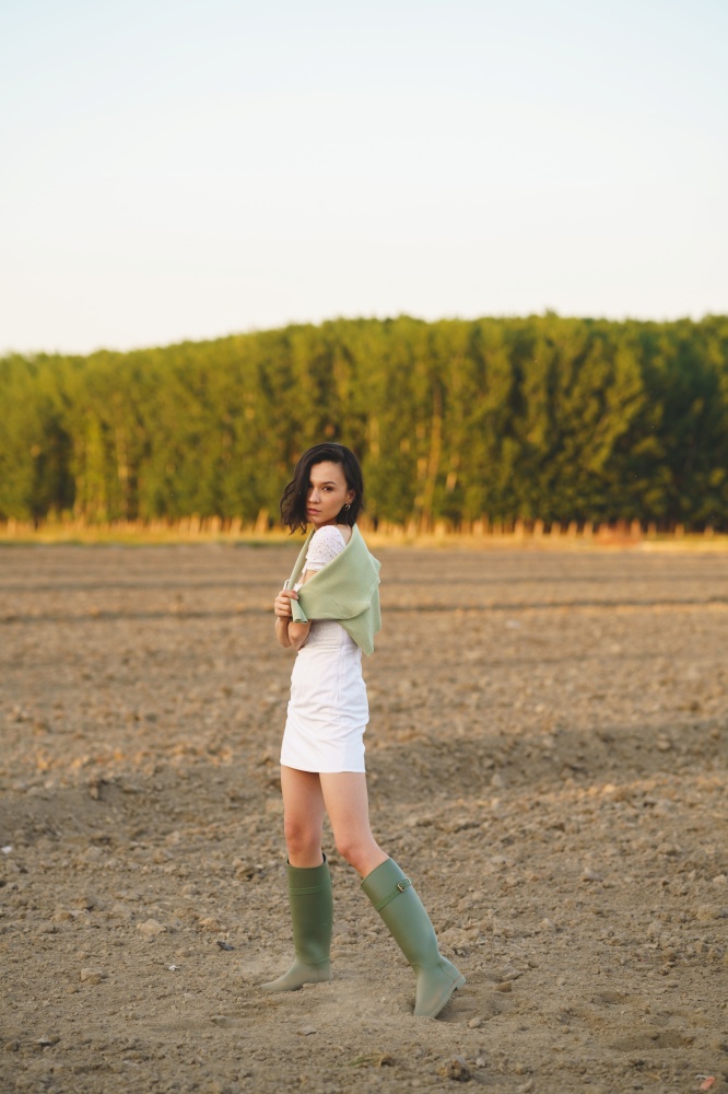 Pretty young Asian woman, walking in the countryside, wearing a white dress and green wellies.. Asian woman, walking in the countryside, wearing a white dress and green wellies.