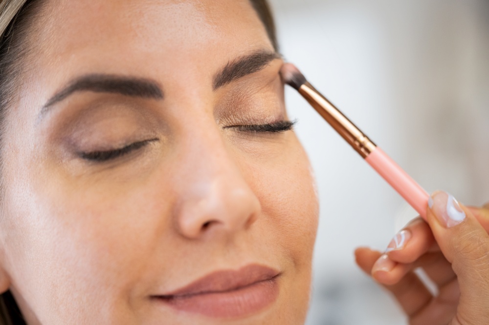 Close-up of a make-up artist applying eye shadow to her client. Beauty and Aesthetic concepts.. Close-up of a make-up artist applying eye shadow to her client.
