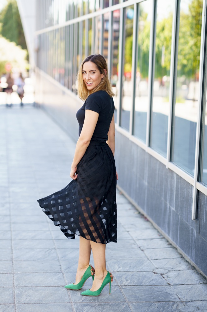 Attractive woman wearing skirt and green high heels on the street.. Attractive woman wearing skirt and green high heels outdoors.