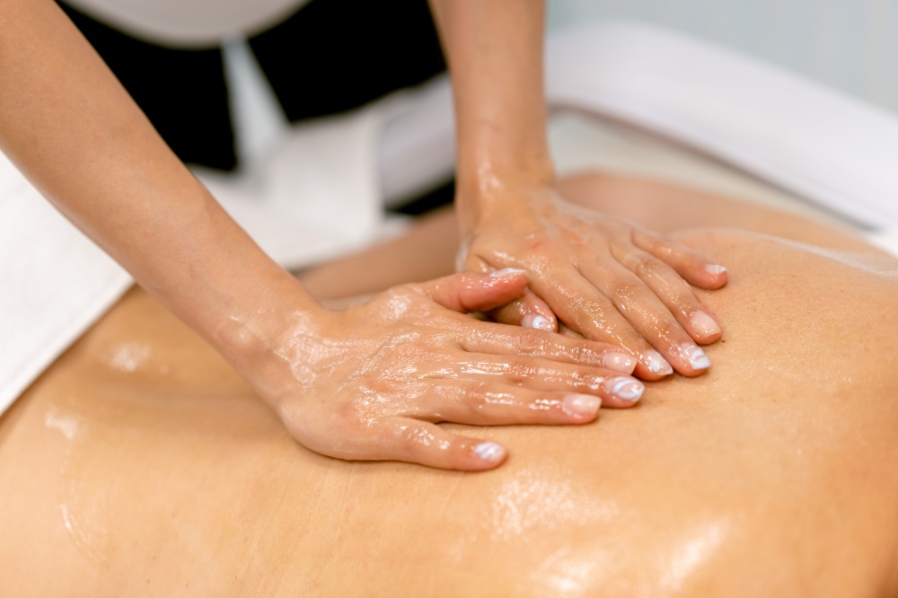 Woman receiving a back massage with massage candle oil. Body care treatment in a beauty centre.. Woman receiving a back massage with massage candle oil.