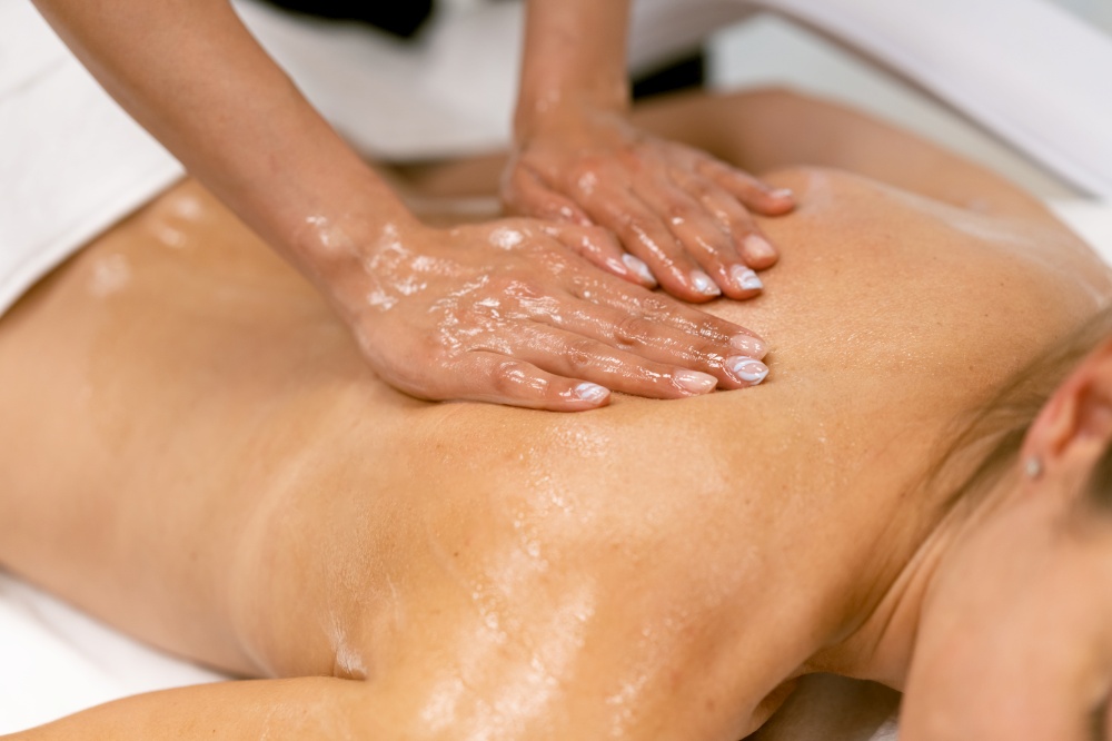 Woman receiving a back massage with massage candle oil. Body care treatment in a beauty centre.. Woman receiving a back massage with massage candle oil.