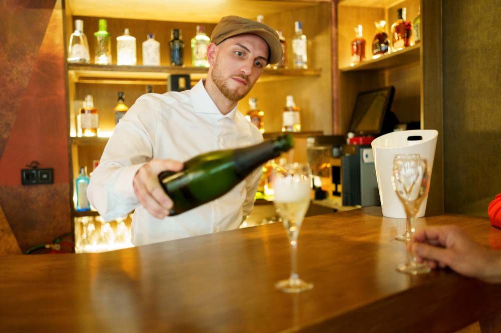 Elegant male bartender pouring sparkling champagne in glasses placed on wooden counter in luxury bar with crop unrecognizable client. Barman pouring drink in glasses in bar