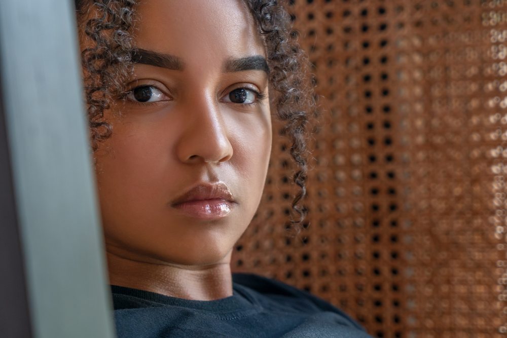 Indoor portrait of beautiful happy mixed race African American girl teenager female thoughtful, sad or depressed, young woman