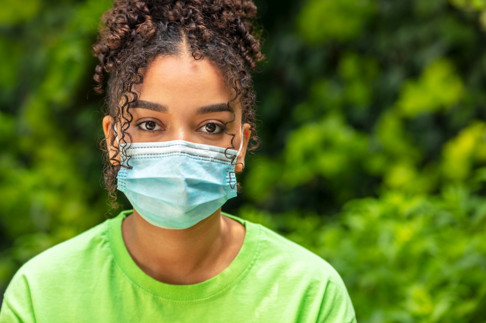 Girl teenager teen mixed race biracial African American female young woman wearing face mask in Coronavirus COVID-19 pandemic