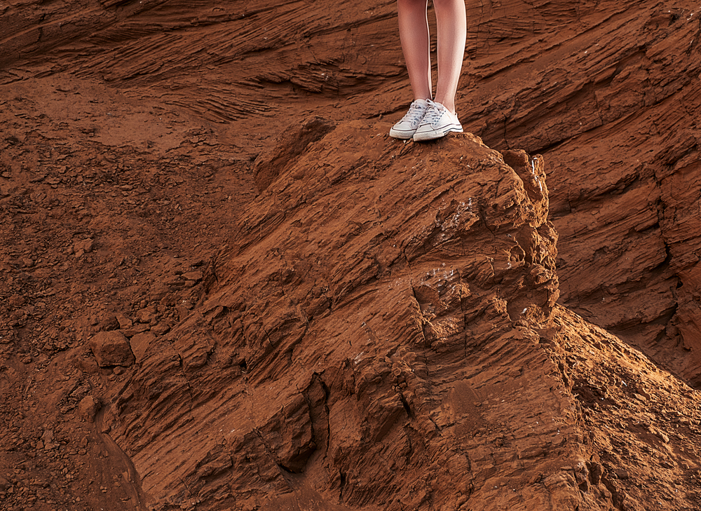 Girl standing on hill slope in canvas trainers