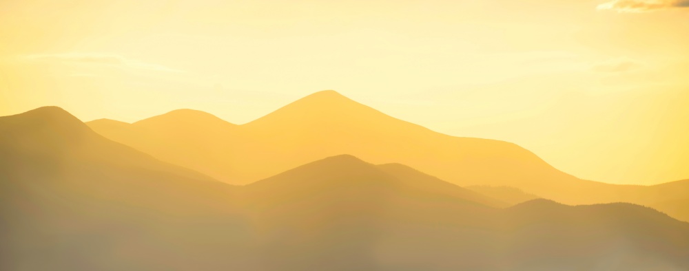 Mountains panorama sunset. Landscape with sun shining through yellow clouds