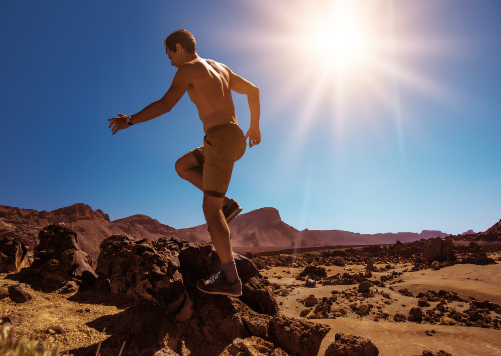 Handsome, muscular man running on the desert mountains
