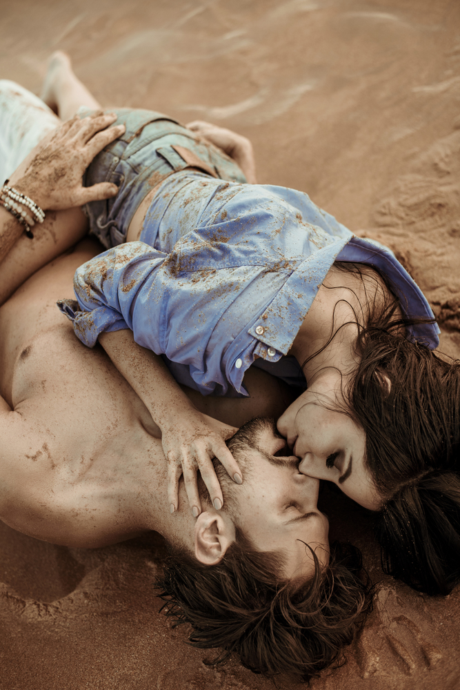 Sensual, young couple laying on the tropical sand